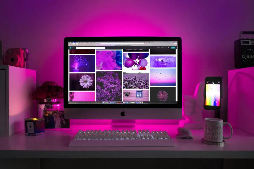 Computer screen and keyboard in front of a purple-lit wall