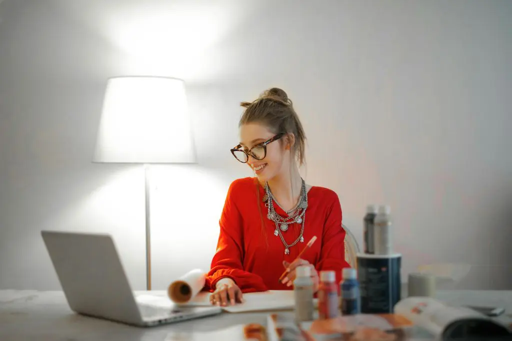 Woman smiling whilst working on a laptop at desk